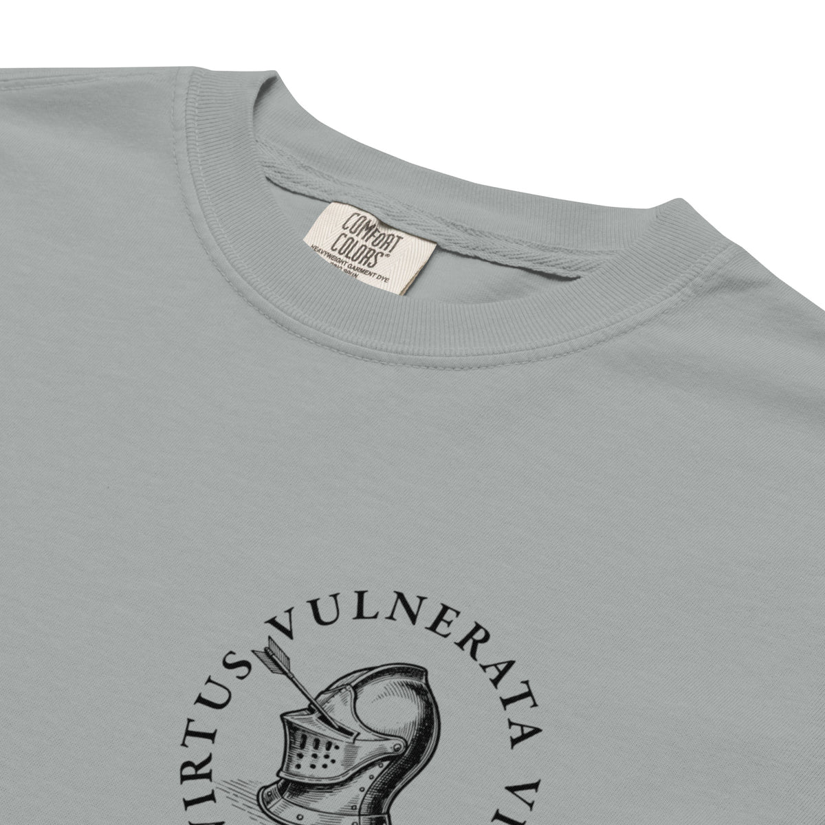 Minimalist graphic t-shirt featuring an illustrated medieval knight pierced by arrows with the Latin phrase Virtus Vulnerata Vincit (“Virtue, though wounded, conquers”).
