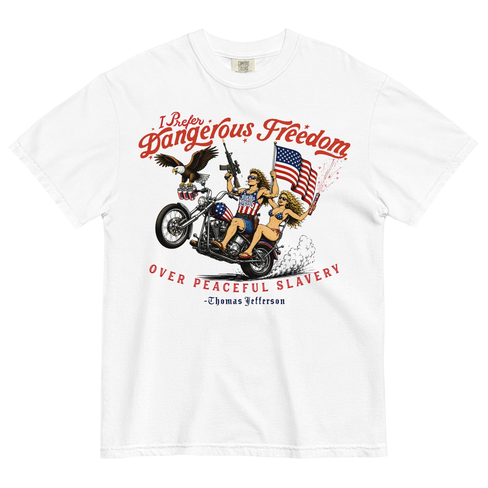 A white short-sleeve crewneck t-shirt featuring a retro-style illustration of a man and women on a motorcycle with American flags, an eagle, and fireworks. Red text above reads 'I Prefer Dangerous Freedom' and text below reads 'OVER PEACEFUL SLAVERY -Thomas Jefferson'. By Liberty Maniacs