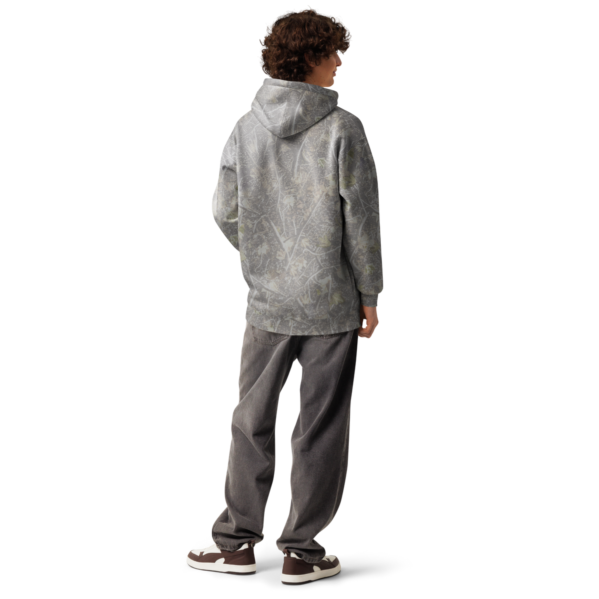 A person shown from the back wearing a gray hooded sweatshirt with a subtle tonal abstract pattern, paired with dark gray sweatpants and brown sneakers, against a plain white studio background.
