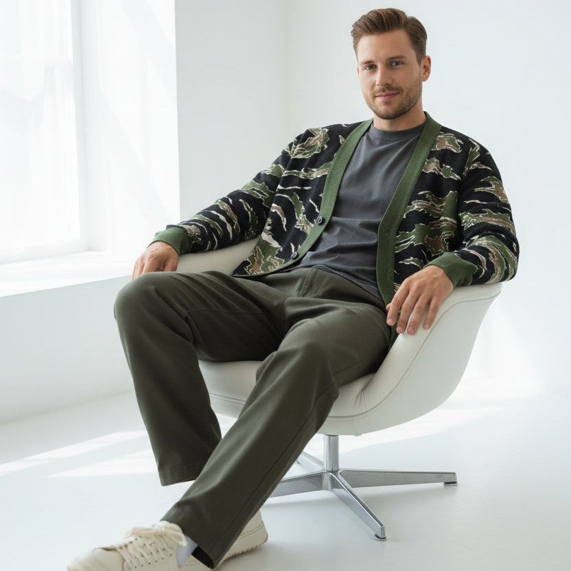 A long-sleeve knit cardigan sweater featuring a tiger stripe camouflage pattern in olive green, black, and tan, with solid olive green ribbed trim and a button-up front.