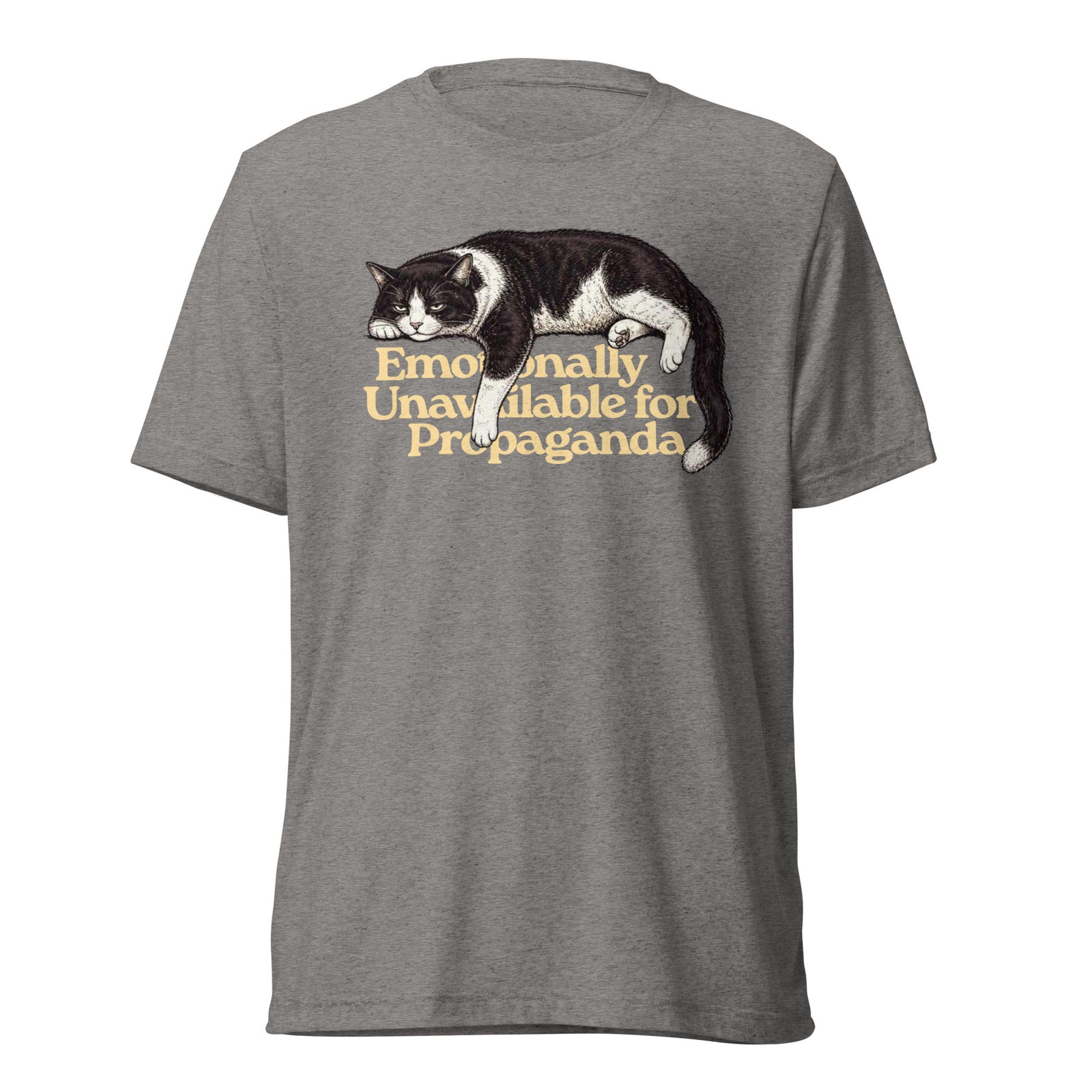 A heather gray short-sleeve t-shirt featuring a graphic of a black and white cat lying down with the text 'Emotionally Unavailable for Propaganda' printed in a warm tan font.