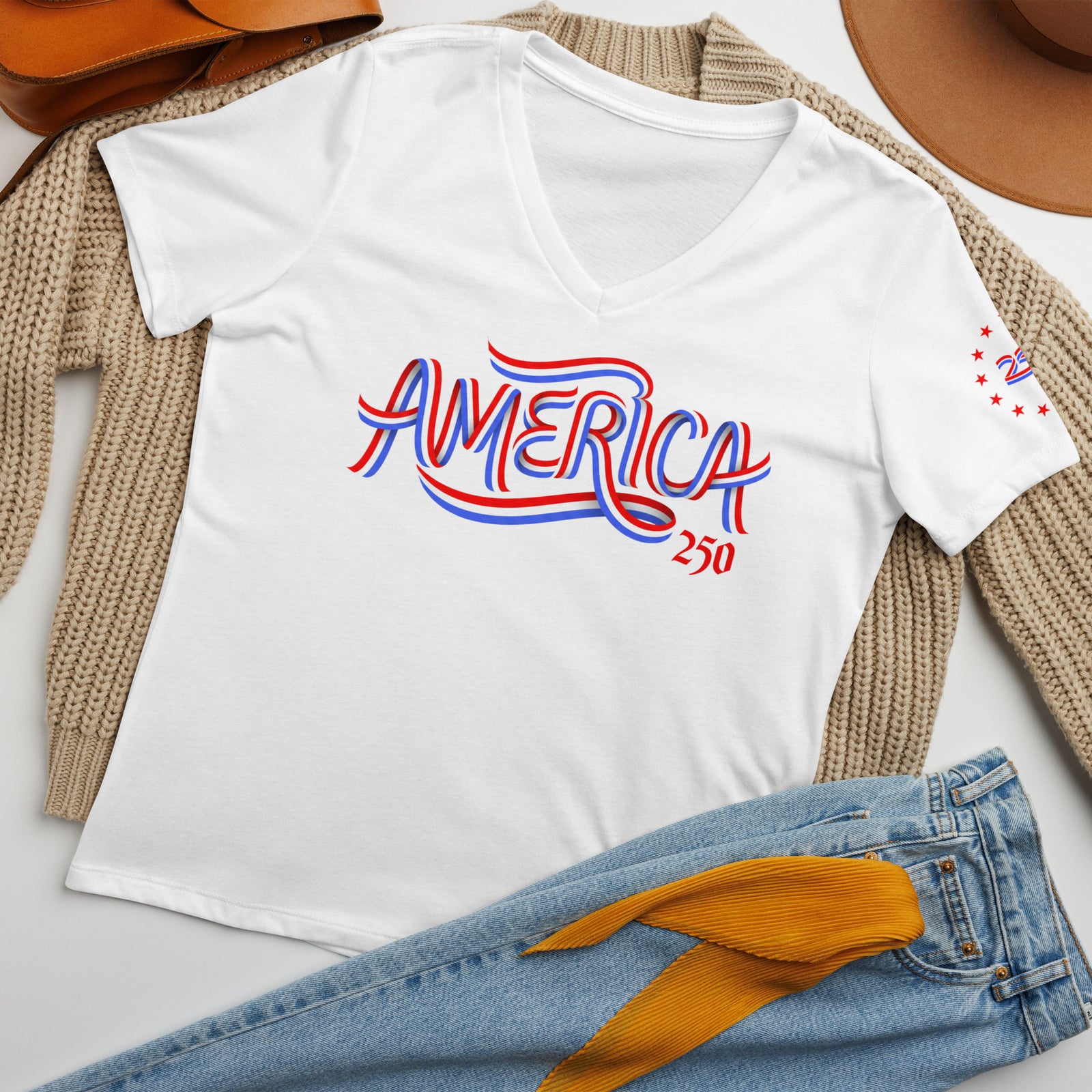 White t-shirt with 'AMERICA 250' text on a surface with jeans and a hat.
