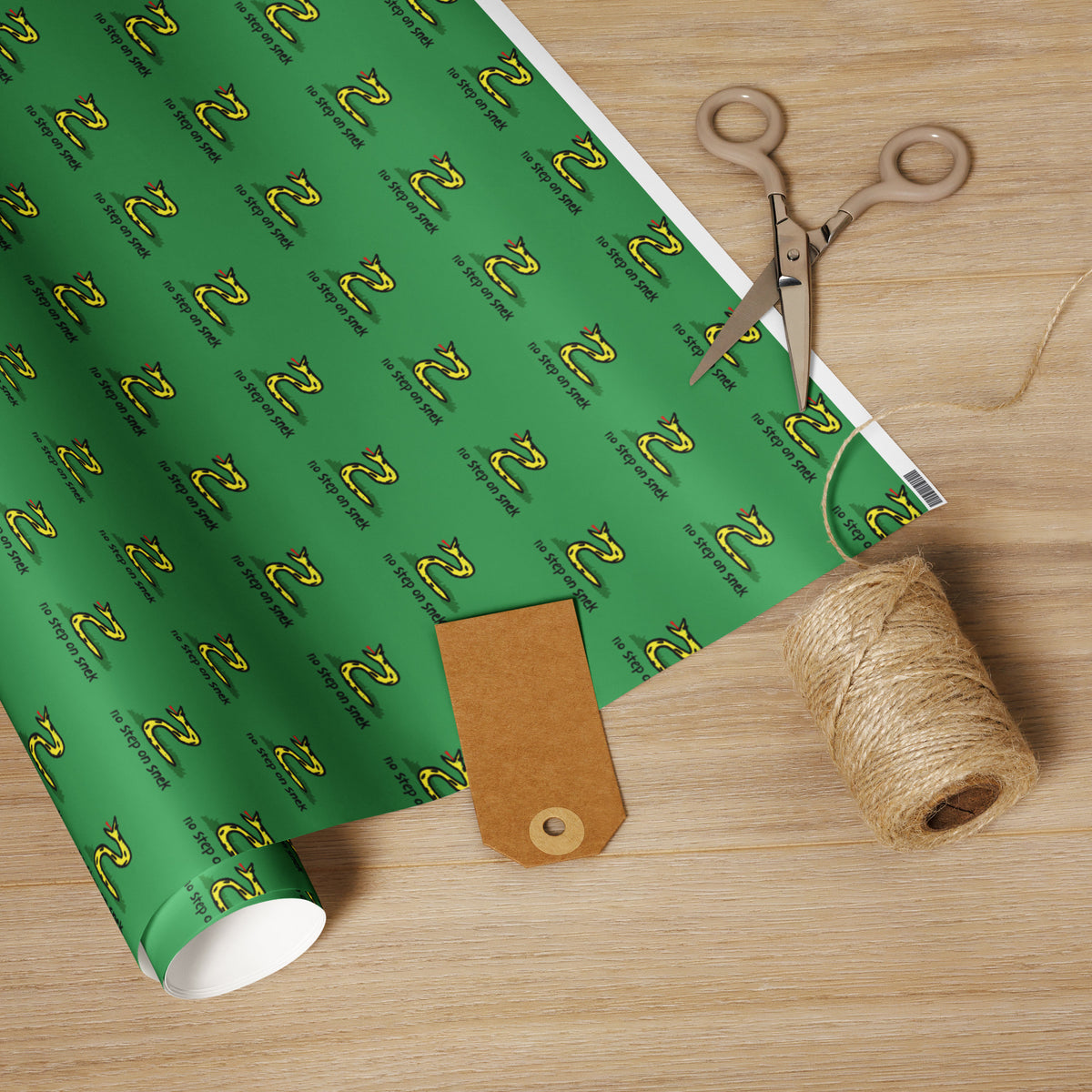 Green wrapping paper with a pattern, scissors, and twine on a wooden surface