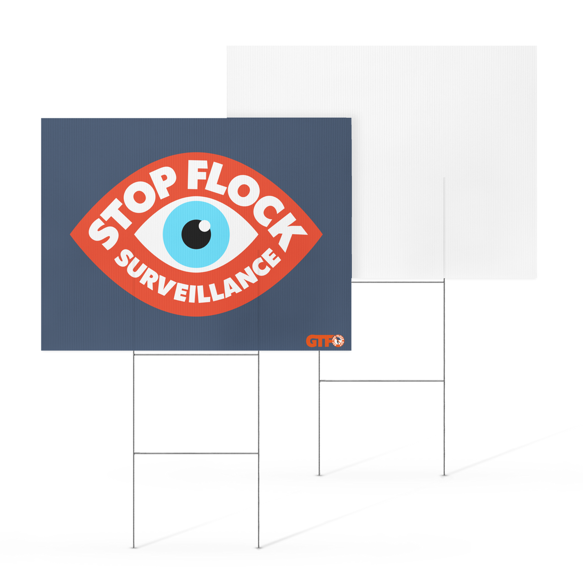 A rectangular yard sign on a metal stand with a dark blue background and a large red eye graphic containing the words “STOP FLOCK SURVEILLANCE.” A second plain white sign is shown behind it on a white studio background.