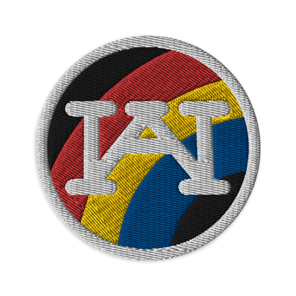 A multicolored embroidered patch with the letters 'WA' in the center, surrounded by a border of red, yellow, and blue colors.
